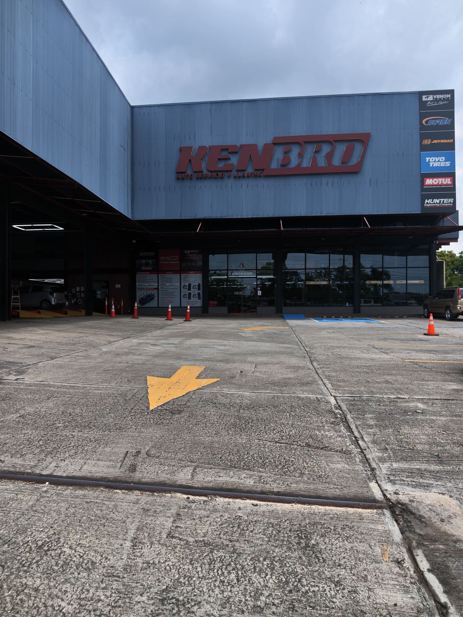 Fachada de Kenbro Auto Servicio y Llantas sobre la Carretera Panamericana, con letrero rojo y columna de marcas Venom, Durun, Joyroad, Toyo, Motul y Hunter